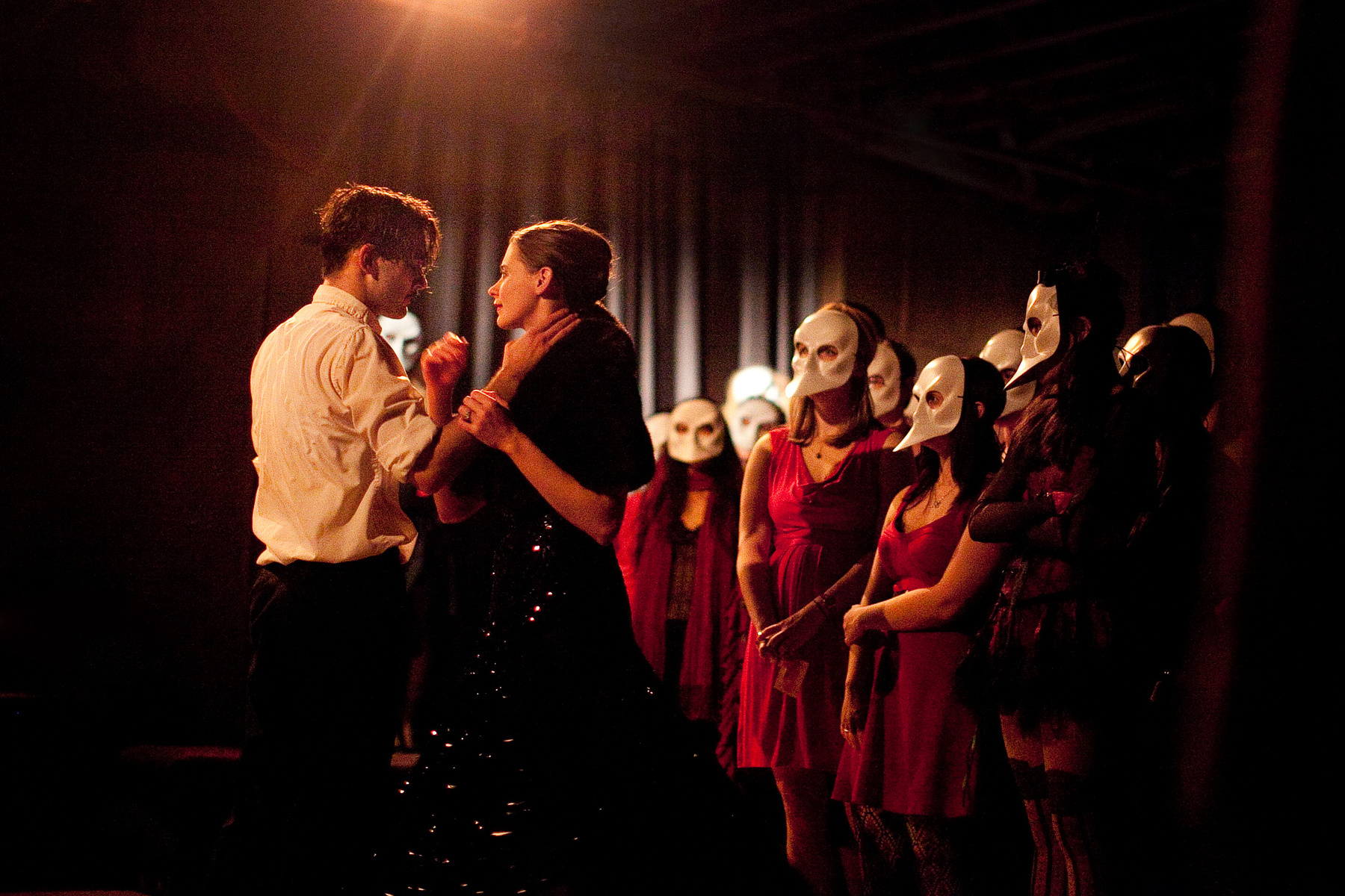 A image of two performers performing infront of a crowd of audience with masks on. This is a scene from the immersive show called sleep no more.